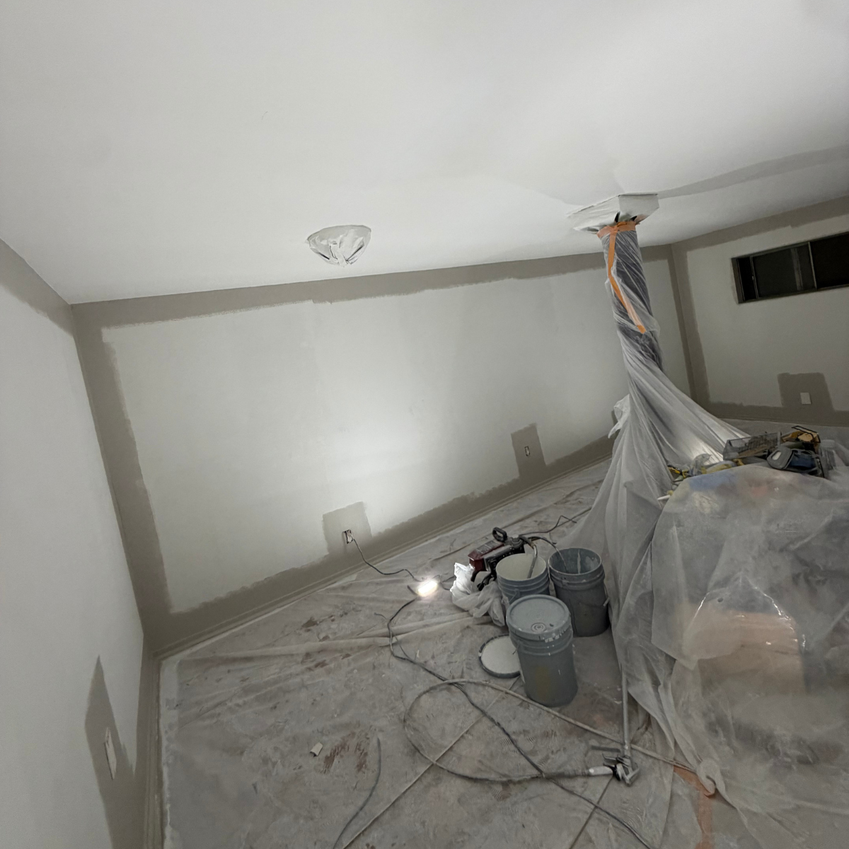 Painter rolling navy paint on a wall